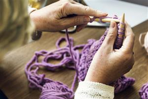 Knitting with purple yarn.